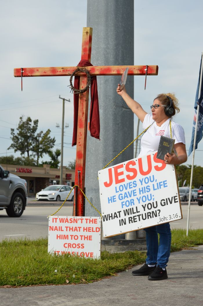 Services Woman evangelizing with religious signs and Bible on a busy street corner.
