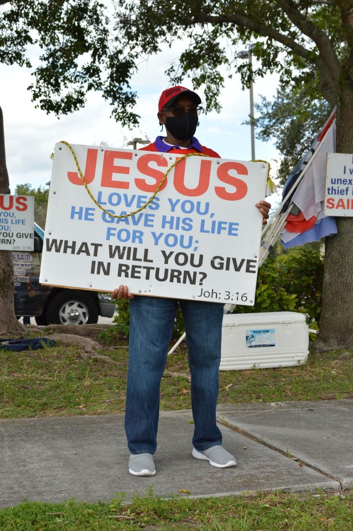 About A man holding a Jesus-themed sign outdoors, promoting religious messages.